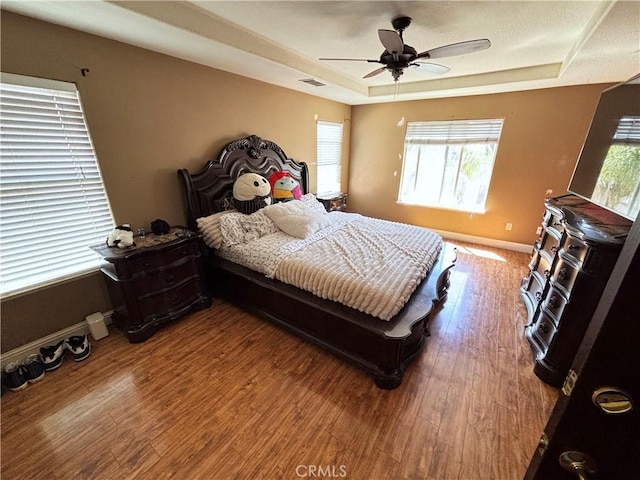 343 San Bernardino St, Los Banos, CA 93635 - bedroom featuring a tray ceiling, baseboards, wood finished floors, and ceiling fan