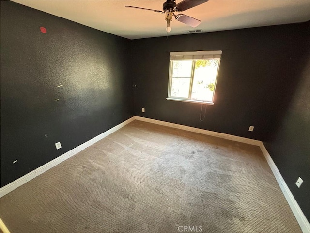 spare room with ceiling fan, visible vents, light carpet, and baseboards
