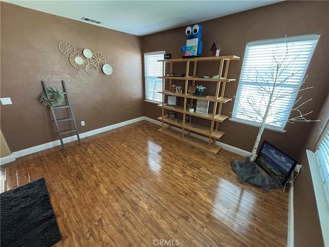 interior space with baseboards, visible vents, and wood finished floors
