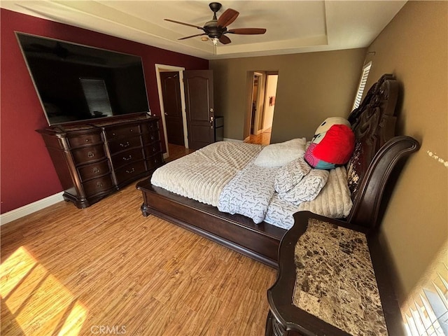 bedroom featuring baseboards, a raised ceiling, ceiling fan, and wood finished floors