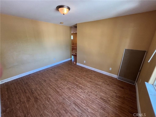 spare room with baseboards and wood finished floors