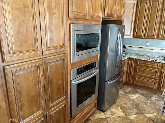 343 San Bernardino St, Los Banos, CA 93635 - kitchen with stainless steel appliances, brown cabinets, light stone countertops, and light stone finish floors