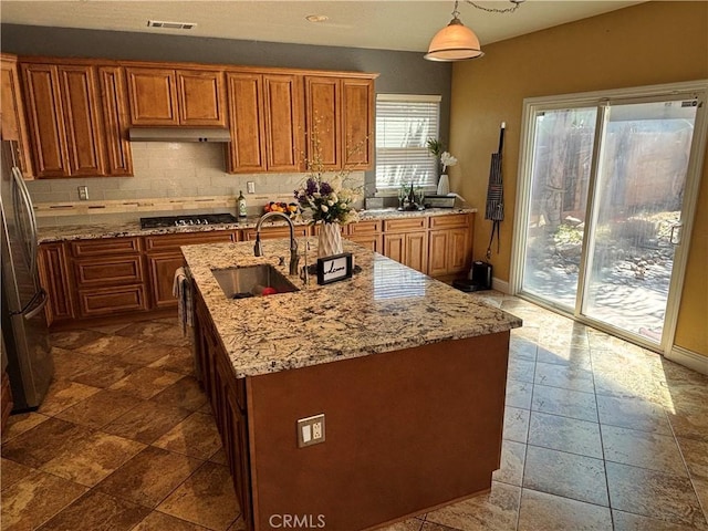 kitchen with visible vents, a sink, backsplash, and brown cabinets