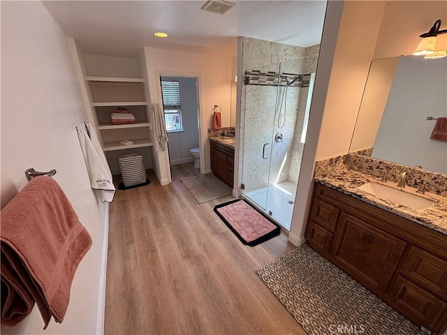 full bathroom with a stall shower, visible vents, wood finished floors, and vanity