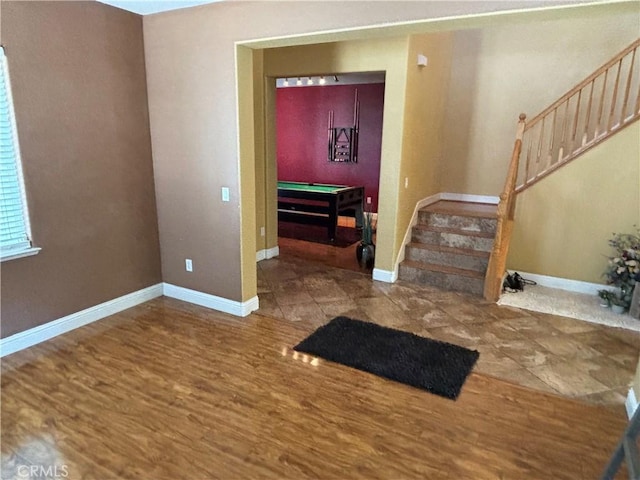 foyer entrance featuring billiards, baseboards, stairs, and wood finished floors