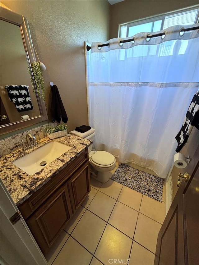 full bath featuring a textured wall, vanity, toilet, tile patterned floors, and a shower with curtain