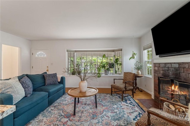 living area with a brick fireplace, baseboards, and wood finished floors