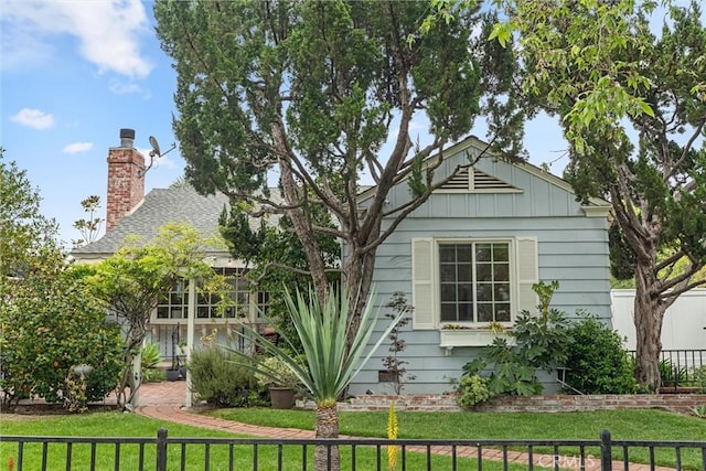 view of front of home featuring a front lawn, board and batten siding, fence, and a chimney