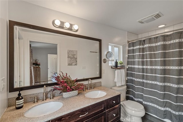 full bath with visible vents, a sink, double vanity, and toilet