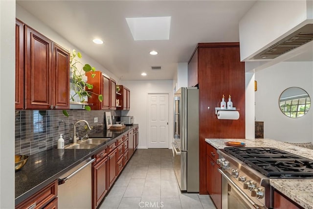 kitchen with appliances with stainless steel finishes, tasteful backsplash, a sink, light tile patterned floors, and stone counters