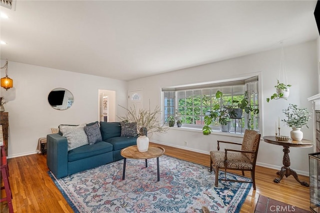 living room featuring baseboards, visible vents, wood finished floors, and a fireplace