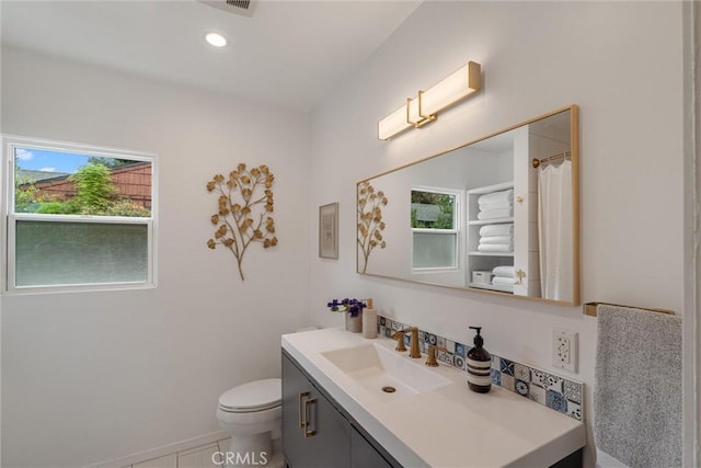 bathroom featuring toilet, plenty of natural light, and vanity