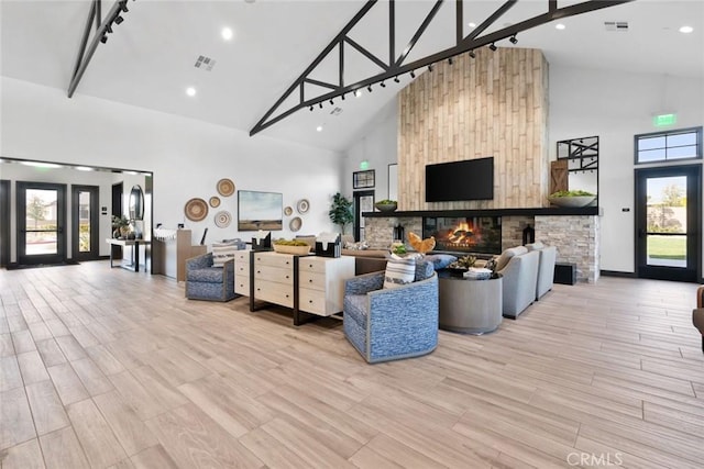 living room with visible vents, a fireplace, and high vaulted ceiling