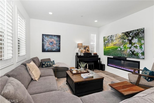 living room featuring recessed lighting, a glass covered fireplace, and wood finished floors