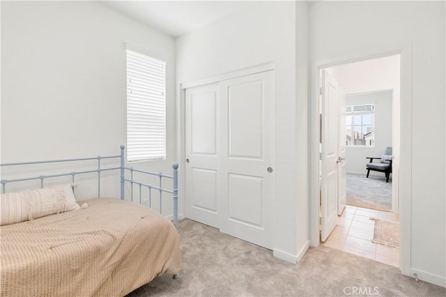bedroom featuring light colored carpet, baseboards, and a closet