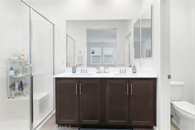 bathroom with a sink, a shower stall, toilet, and double vanity