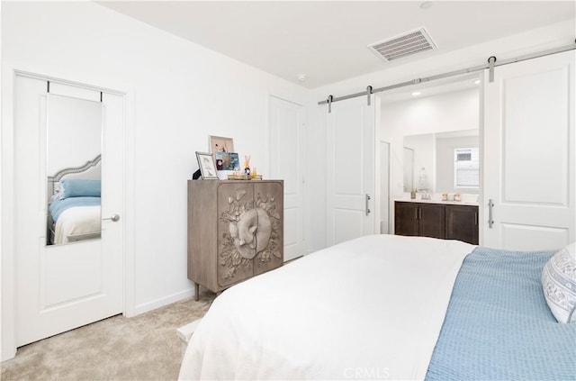 bedroom featuring light colored carpet, a barn door, ensuite bath, baseboards, and visible vents