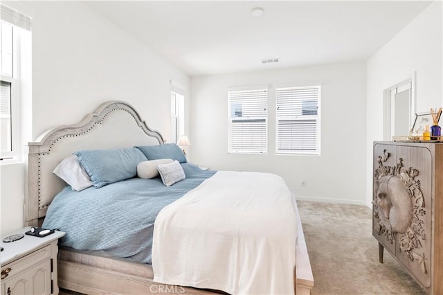 bedroom with visible vents, baseboards, and light carpet