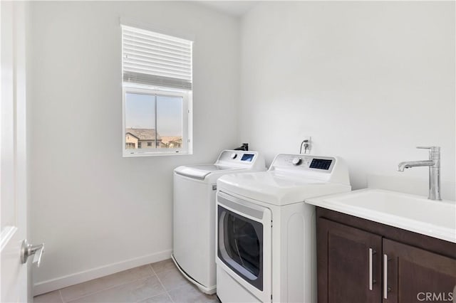 washroom with washer and dryer, baseboards, a sink, cabinet space, and light tile patterned floors