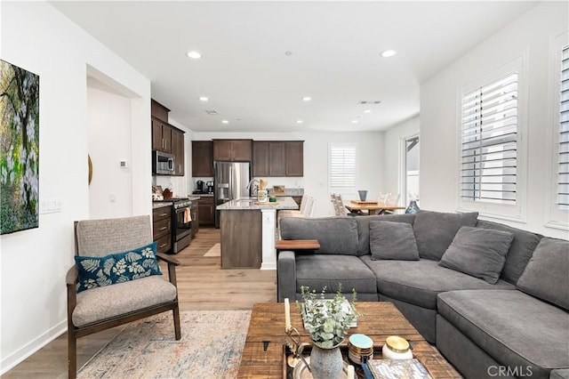 living room with baseboards, recessed lighting, light wood-style flooring, and visible vents