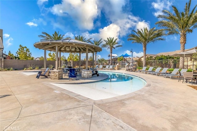 community pool with fence, a gazebo, and a patio area
