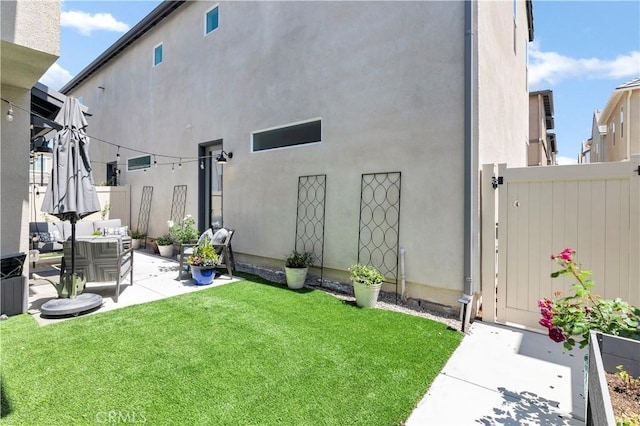 rear view of property with a lawn, fence, an outdoor living space, and stucco siding
