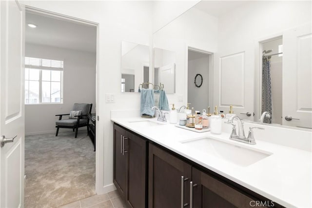 full bathroom featuring a sink, baseboards, and double vanity
