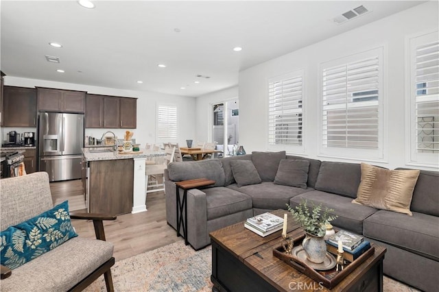 living area with visible vents, recessed lighting, and light wood-style flooring