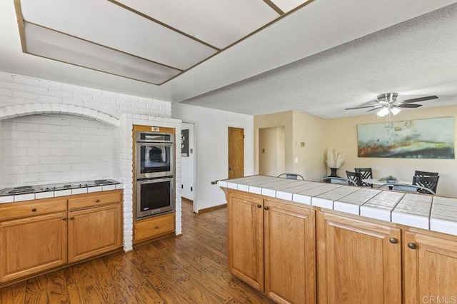 68256827 Kellyn Ln, Vista, CA 92084 - kitchen featuring dark wood-style flooring, tile counters, black electric stovetop, and double oven