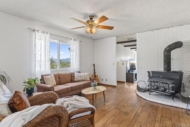 68256827 Kellyn Ln, Vista, CA 92084 - living room featuring a wood stove, a textured ceiling, a ceiling fan, and hardwood / wood-style floors