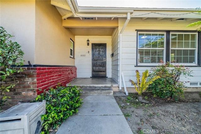 property entrance with a porch and stucco siding