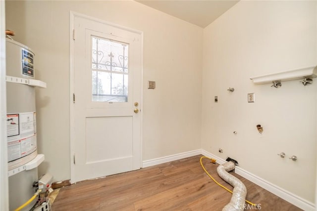 laundry room featuring laundry area, strapped water heater, baseboards, and light wood-type flooring