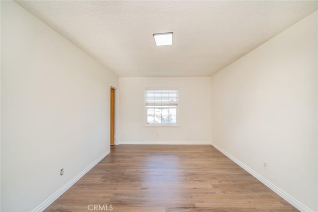 unfurnished room with baseboards and light wood finished floors
