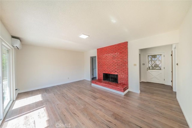 unfurnished living room featuring a wall mounted AC, a healthy amount of sunlight, and light wood-type flooring