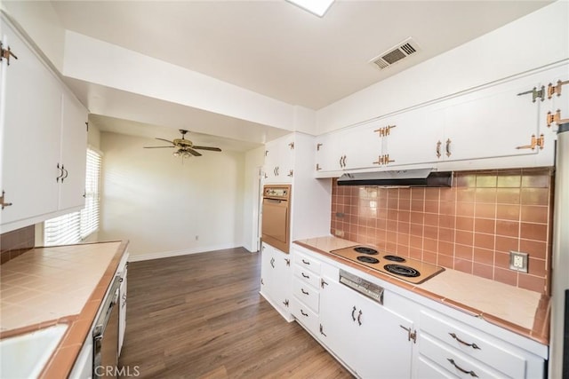 kitchen with visible vents, wall oven, tile counters, under cabinet range hood, and backsplash