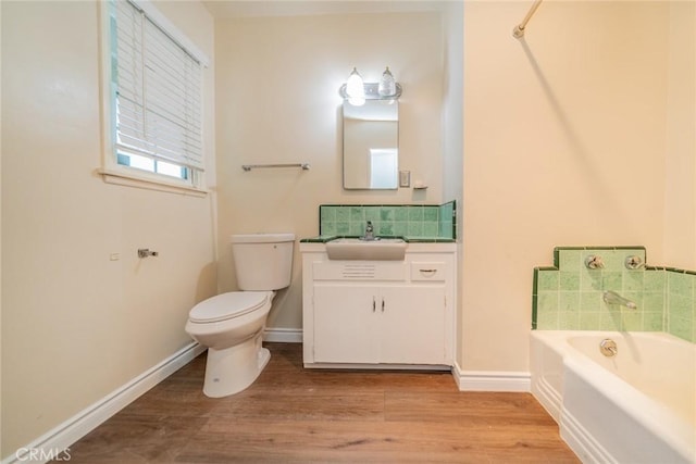 bathroom featuring vanity, toilet, a washtub, baseboards, and wood finished floors