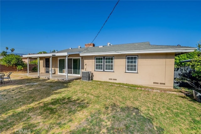 rear view of property featuring central AC, fence, a patio, stucco siding, and a yard