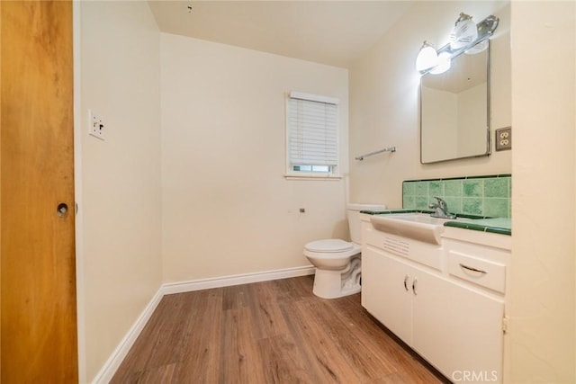 bathroom with vanity, baseboards, wood finished floors, and toilet