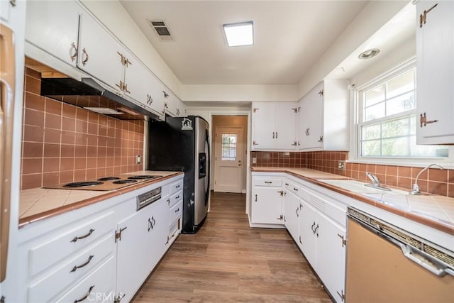 kitchen featuring tile counters, electric stovetop, dishwasher, and visible vents