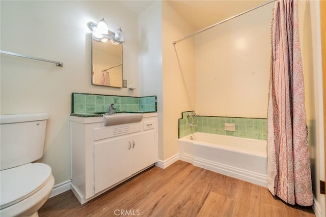 bathroom with vanity, wood finished floors, toilet, a shower with shower curtain, and a bathtub