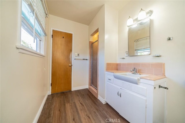 full bathroom featuring wood finished floors, baseboards, backsplash, and a stall shower
