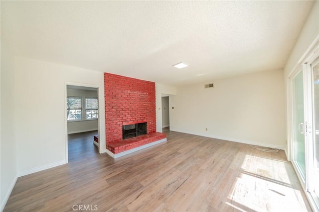 unfurnished living room featuring baseboards, a fireplace, light wood-style flooring, and visible vents