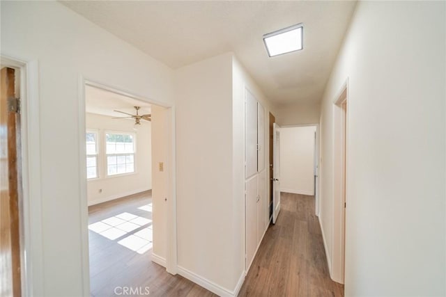 hallway featuring baseboards and light wood finished floors