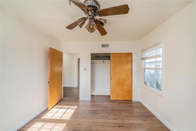 unfurnished bedroom with a closet, baseboards, visible vents, and light wood-style floors