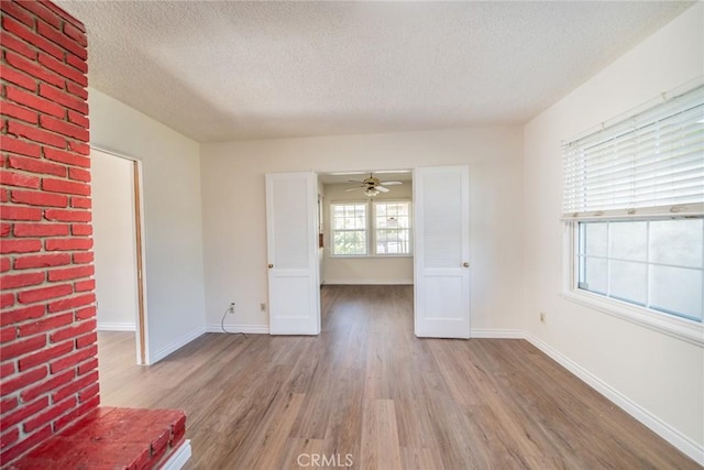 spare room with baseboards, a ceiling fan, a textured ceiling, and wood finished floors