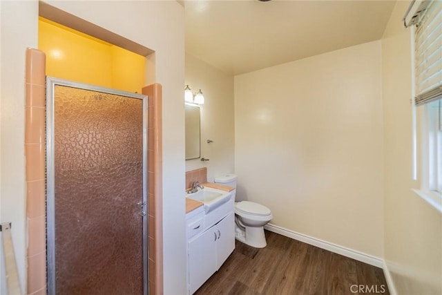bathroom featuring vanity, wood finished floors, toilet, baseboards, and a stall shower