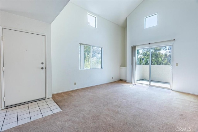 interior space featuring high vaulted ceiling, baseboards, and light colored carpet