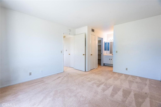 unfurnished bedroom featuring visible vents, connected bathroom, baseboards, and light carpet