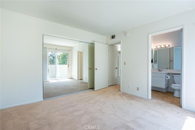 unfurnished bedroom featuring visible vents, light colored carpet, a sink, access to outside, and ensuite bath