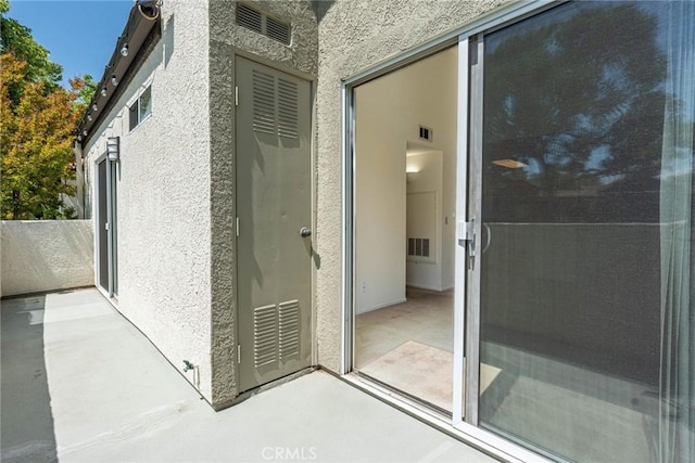 entrance to property featuring visible vents and stucco siding